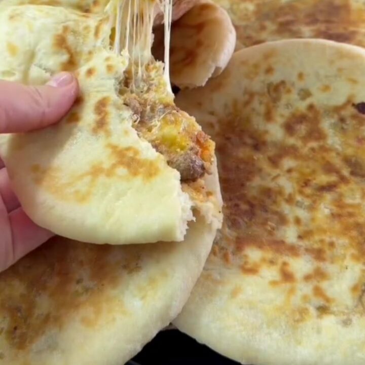 Golden pan-toasted Turkish flatbread cut in half, showing juicy spiced beef and melted cheese