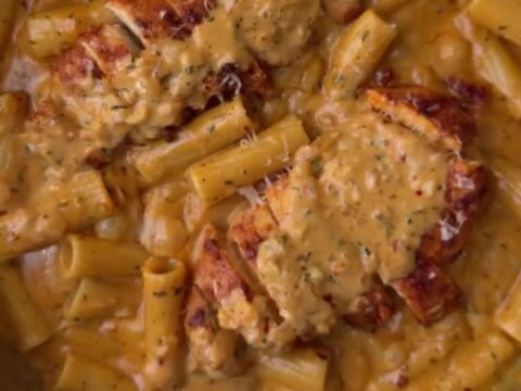 Creamy garlic parmesan chicken fettuccine in a skillet, topped with sliced chicken and parsley