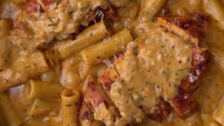 Creamy garlic parmesan chicken fettuccine in a skillet, topped with sliced chicken and parsley