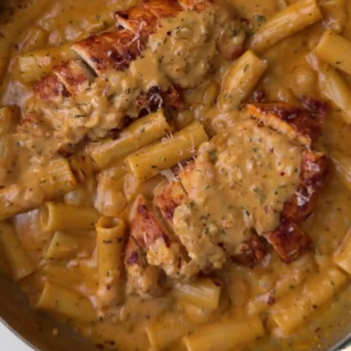 Creamy garlic parmesan chicken fettuccine in a skillet, topped with sliced chicken and parsley