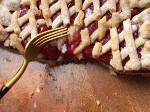 Slice of strawberry chocolate tart with lattice top and powdered sugar