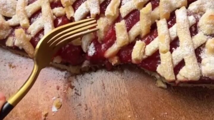 Slice of strawberry chocolate tart with lattice top and powdered sugar