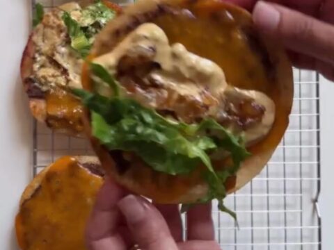 Crispy smash burger tacos with melted cheddar, shredded lettuce, and pink animal sauce on a plate