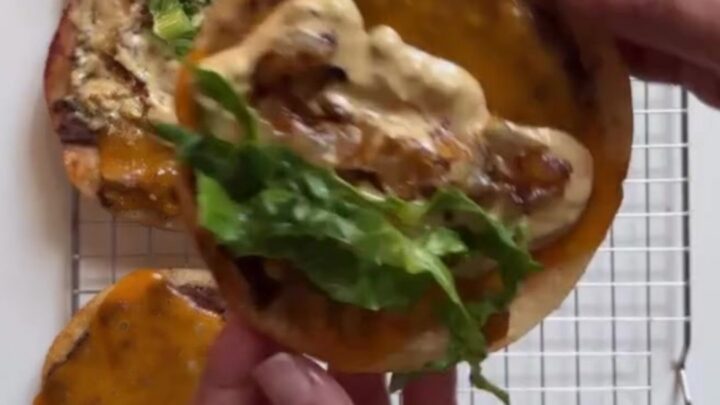 Crispy smash burger tacos with melted cheddar, shredded lettuce, and pink animal sauce on a plate