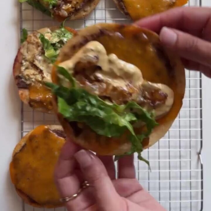 Crispy smash burger tacos with melted cheddar, shredded lettuce, and pink animal sauce on a plate