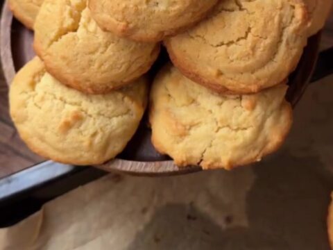 Golden coconut lemon white chocolate cookies on a wire rack, with melted chocolate visible in the center