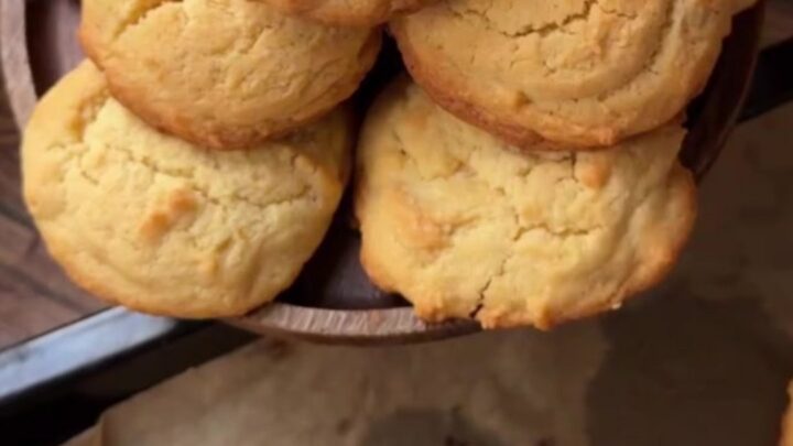 Golden coconut lemon white chocolate cookies on a wire rack, with melted chocolate visible in the center