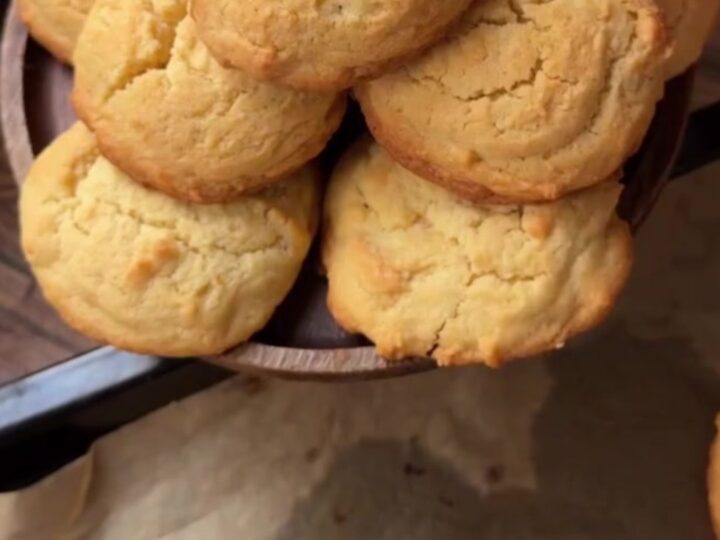 Golden coconut lemon white chocolate cookies on a wire rack, with melted chocolate visible in the center
