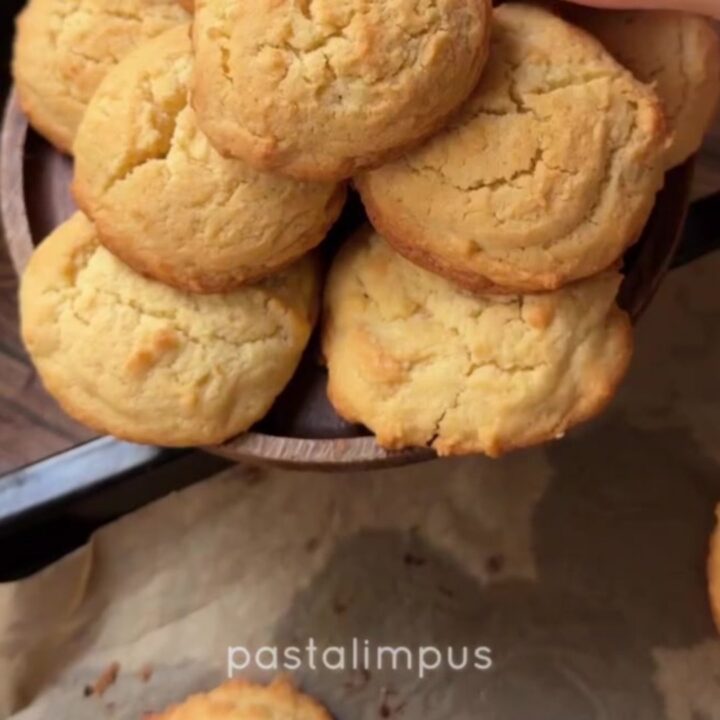 Golden coconut lemon white chocolate cookies on a wire rack, with melted chocolate visible in the center