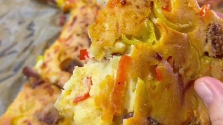Golden sheet pan crepe pizza topped with melted cheese, sucuk slices, peppers, and corn
