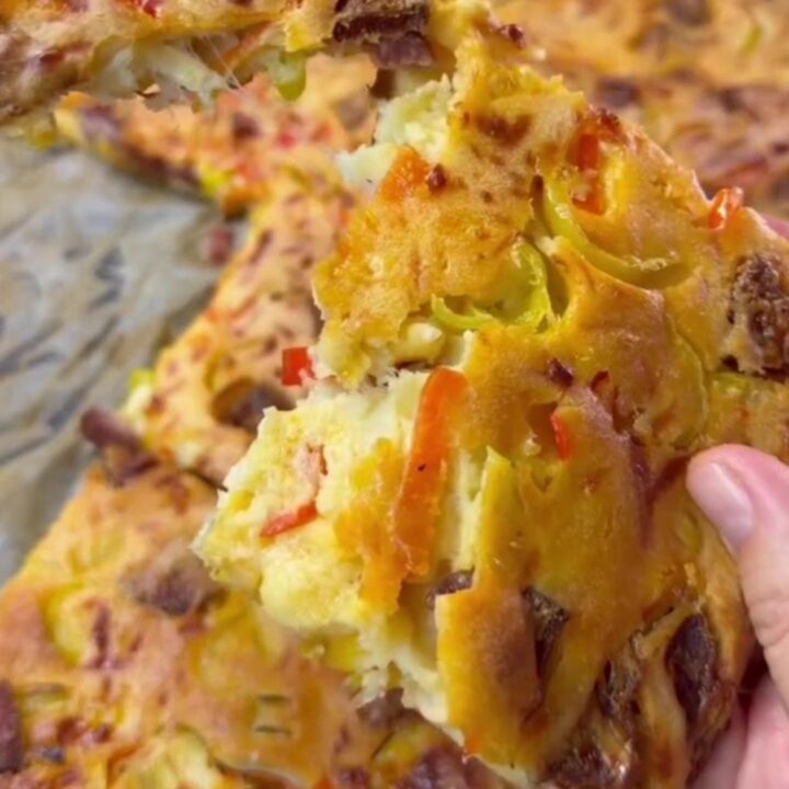 Golden sheet pan crepe pizza topped with melted cheese, sucuk slices, peppers, and corn