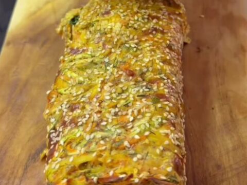 Crispy baked potato roulade sliced into rounds, showing creamy labneh, lettuce, tomato, red onion, and boiled egg layers.