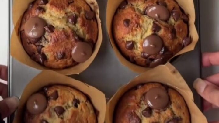 Tall golden banana chocolate chip muffins with melted chocolate chips on top, on a cooling rack