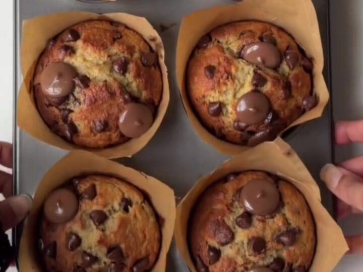 Tall golden banana chocolate chip muffins with melted chocolate chips on top, on a cooling rack