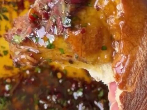A ceramic plate with golden olive oil, balsamic swirls, sun-dried tomatoes, and Parmesan, surrounded by torn sourdough bread.