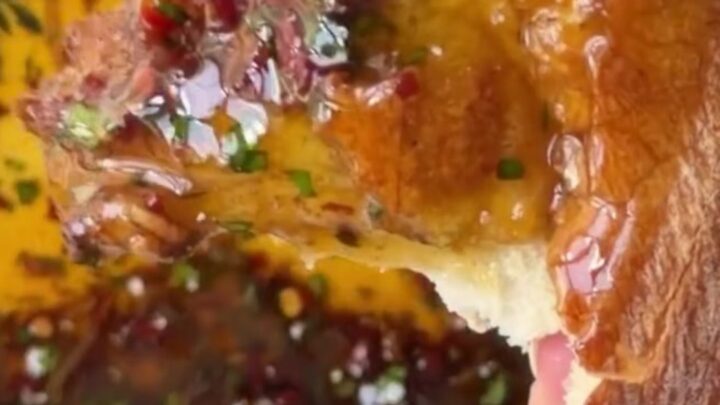 A ceramic plate with golden olive oil, balsamic swirls, sun-dried tomatoes, and Parmesan, surrounded by torn sourdough bread.