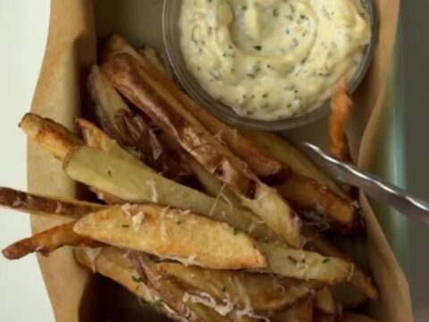 Golden crispy fries tossed with garlic butter, parmesan, and parsley, with a bowl of creamy garlic aioli for dipping.