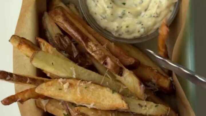Golden crispy fries tossed with garlic butter, parmesan, and parsley, with a bowl of creamy garlic aioli for dipping.