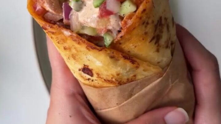 Crispy toasted chicken wrap sliced in half, showing juicy chicken, lettuce, and tomato.