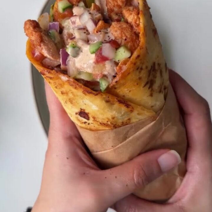 Crispy toasted chicken wrap sliced in half, showing juicy chicken, lettuce, and tomato.