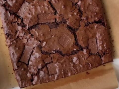 A stack of fudgy brownies with a shiny, crackly top and gooey chocolate center.
