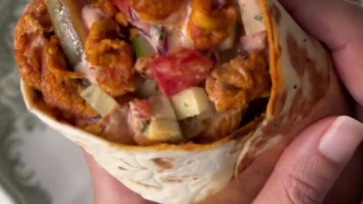 Crispy chicken shawarma wrap cut in half showing juicy chicken, fries, and sauce