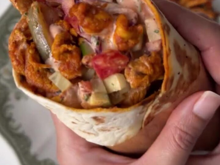 Crispy chicken shawarma wrap cut in half showing juicy chicken, fries, and sauce