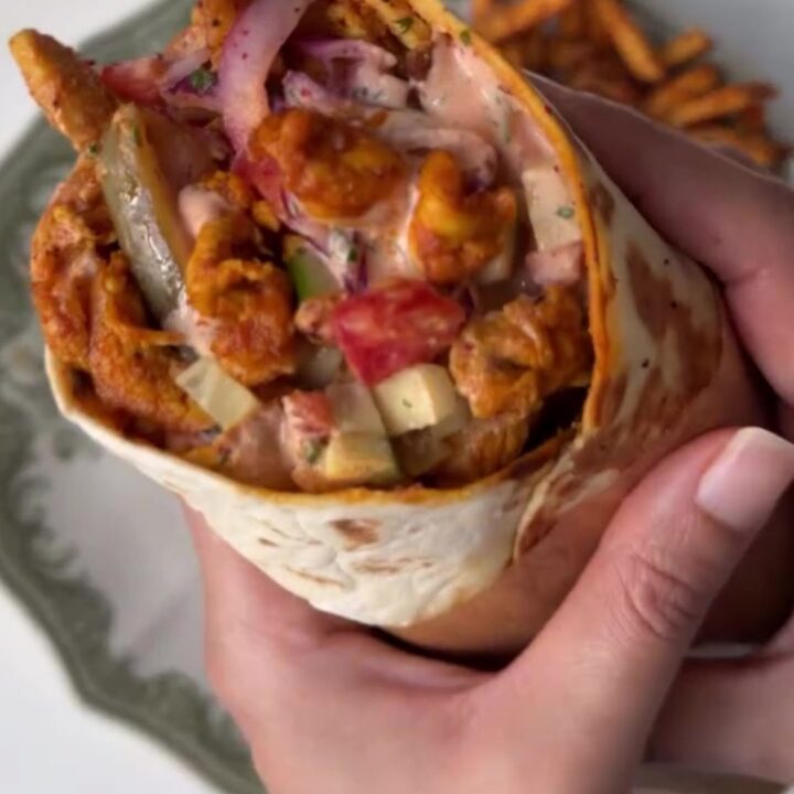 Crispy chicken shawarma wrap cut in half showing juicy chicken, fries, and sauce