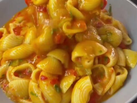 Saucy cheesy pasta in a skillet with blistered tomatoes and melted cheese strings