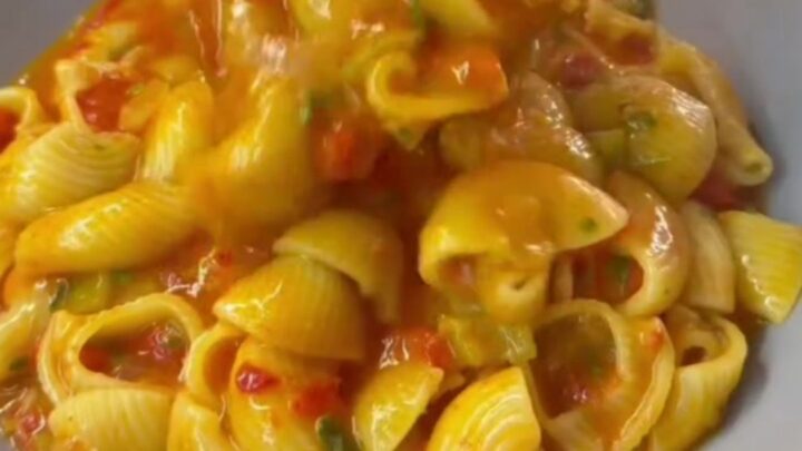 Saucy cheesy pasta in a skillet with blistered tomatoes and melted cheese strings