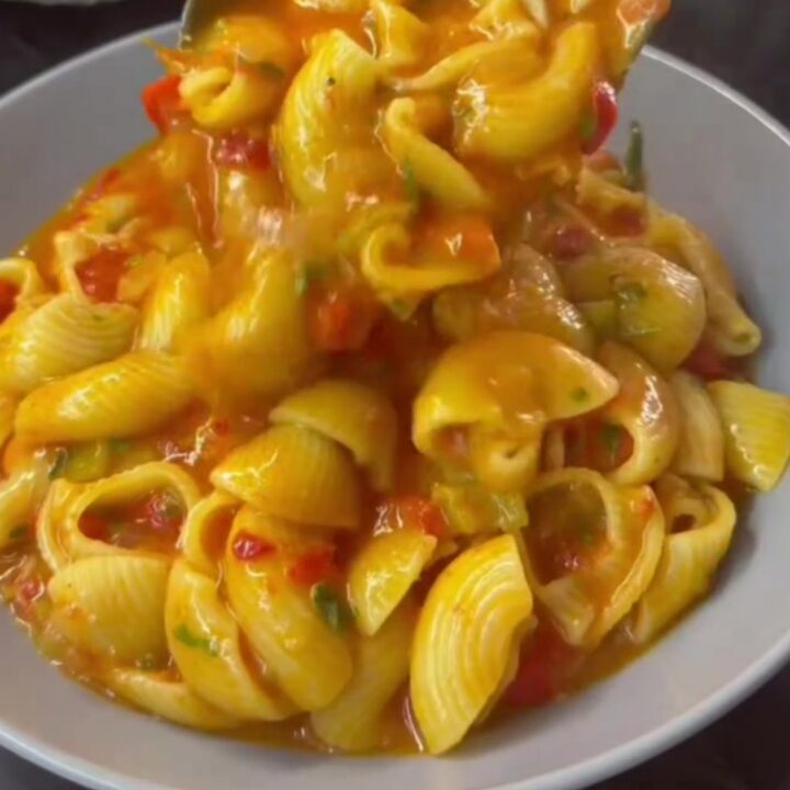 Saucy cheesy pasta in a skillet with blistered tomatoes and melted cheese strings