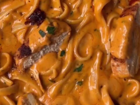 Twirled fettuccine Alfredo with chili crisp and sliced seared chicken, topped with Parmesan