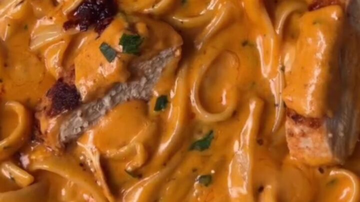 Twirled fettuccine Alfredo with chili crisp and sliced seared chicken, topped with Parmesan