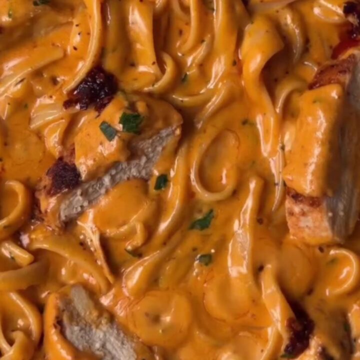 Twirled fettuccine Alfredo with chili crisp and sliced seared chicken, topped with Parmesan