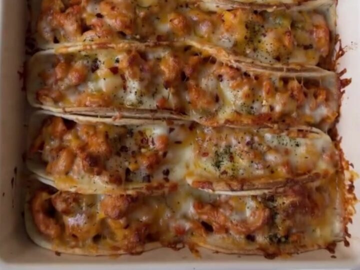 Golden crispy baked chicken tacos on a platter with a bowl of cilantro lime crema for dipping.