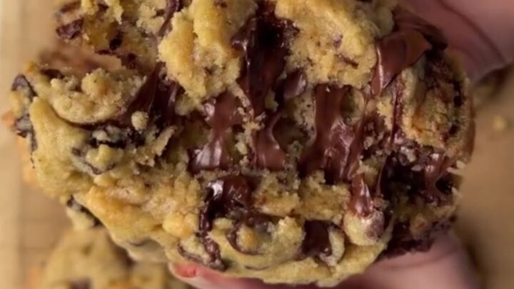 A thick, golden chocolate chip cookie broken open, showing a gooey