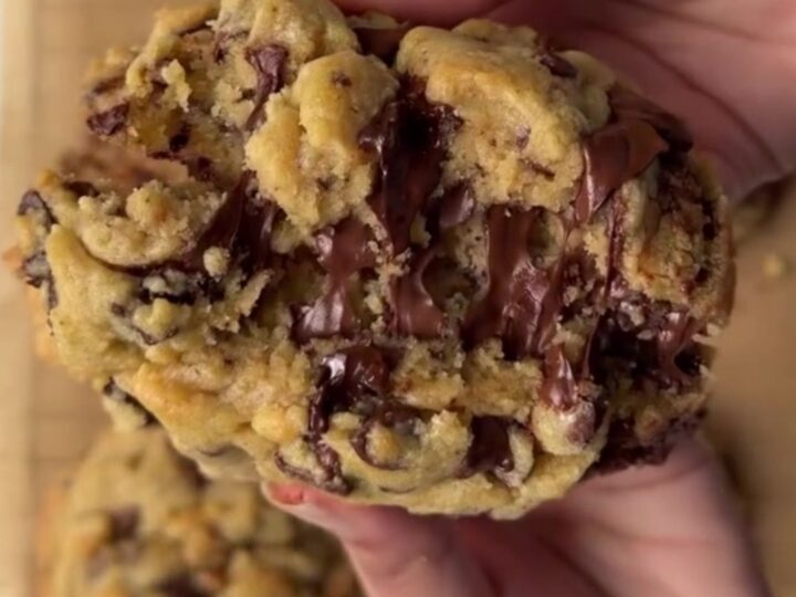A thick, golden chocolate chip cookie broken open, showing a gooey