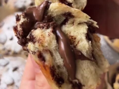 Golden brioche buns with chocolate chips and a molten chocolate hazelnut center, dusted with powdered sugar.