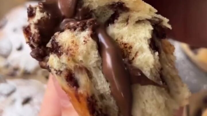 Golden brioche buns with chocolate chips and a molten chocolate hazelnut center, dusted with powdered sugar.