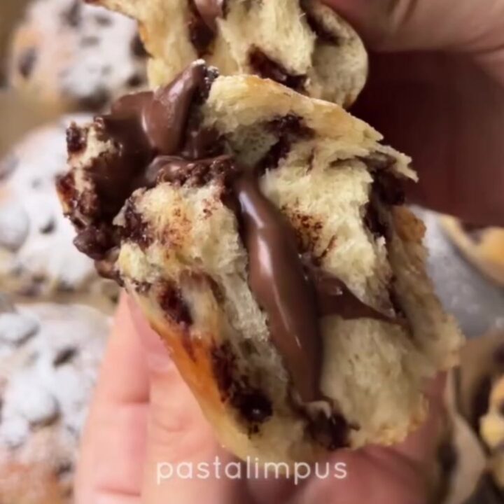 Golden brioche buns with chocolate chips and a molten chocolate hazelnut center, dusted with powdered sugar.