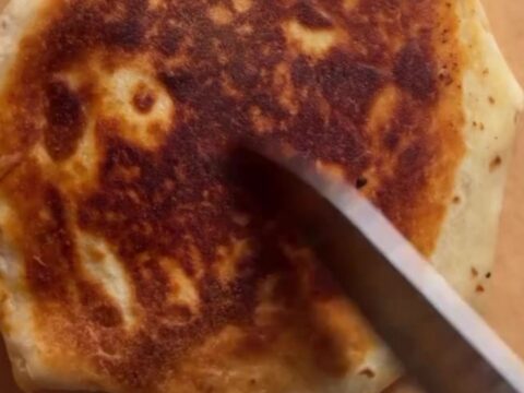 Golden hexagonal Crunchwrap Supreme cut in half showing layers of beef, cheese, tostada, and lettuce.