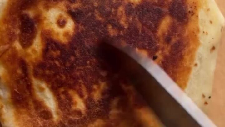 Golden hexagonal Crunchwrap Supreme cut in half showing layers of beef, cheese, tostada, and lettuce.