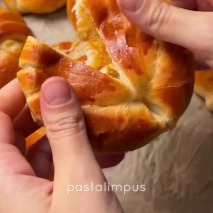 Golden Turkish poğaça buns on a baking sheet, one broken open showing cheese stretch