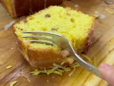 Sliced whole lemon loaf cake with dried fruit on a wooden board