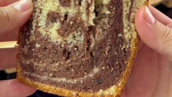 Tall zebra marble loaf cake with hazelnut topping, sliced to show chocolate and vanilla swirls