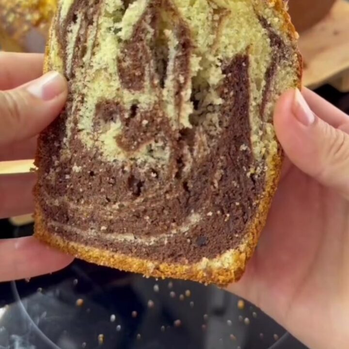 Tall zebra marble loaf cake with hazelnut topping, sliced to show chocolate and vanilla swirls