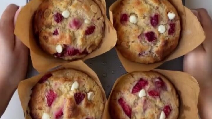 Golden-domed muffin broken open showing molten white chocolate and roasted strawberries