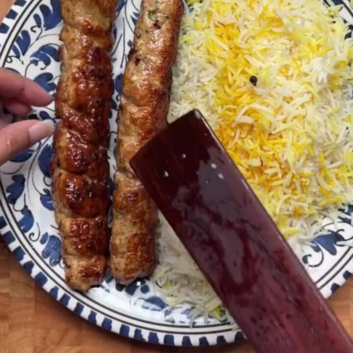 Juicy charred chicken kebabs over saffron rice with cucumber-tomato salad