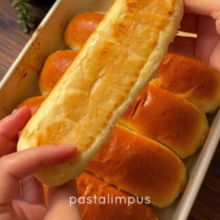 Golden brown homemade sandwich buns on a baking sheet, brushed with butter
