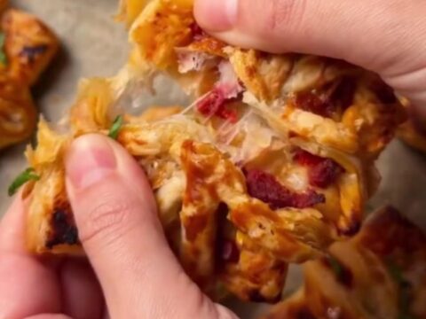 Golden puff pastry pizza flowers with sucuk and peppers on a baking sheet